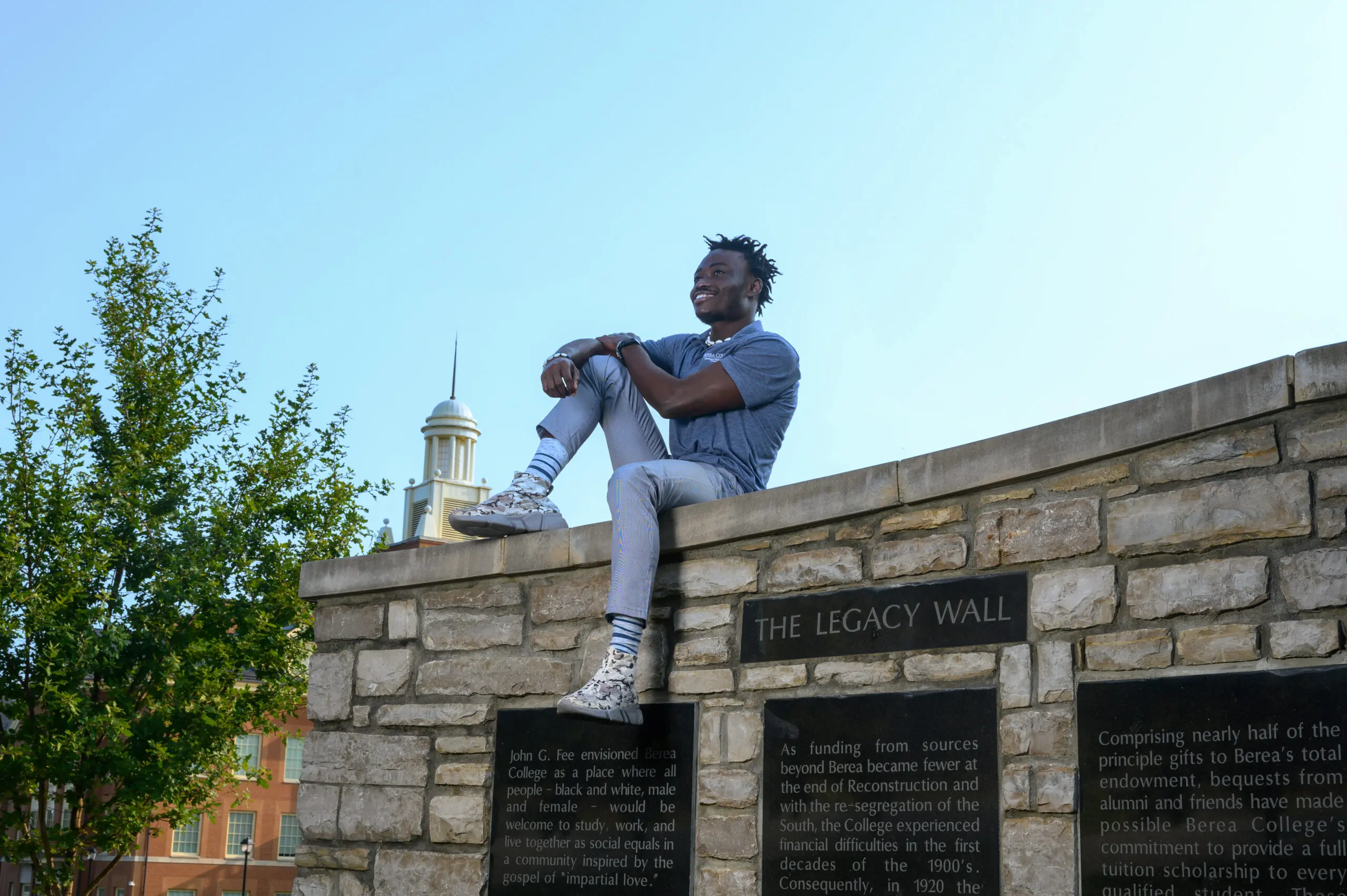 Student sitting on the Legacy Wall.