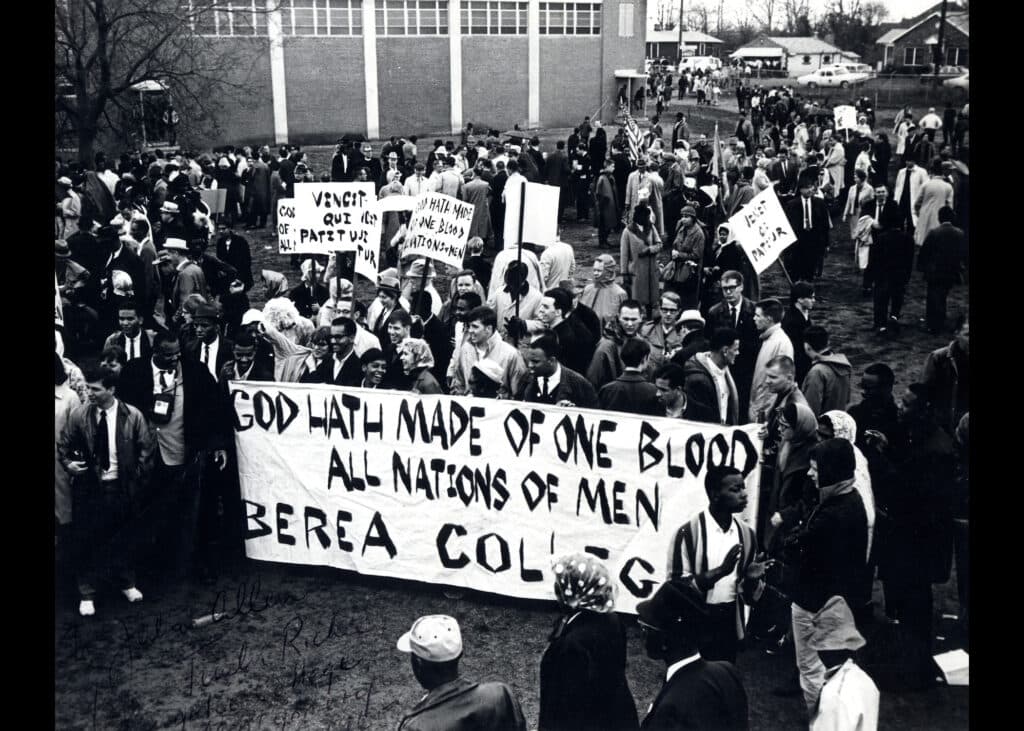 Black and white photo of Berea College students with a banner displaying the motto before heading to the Selma march