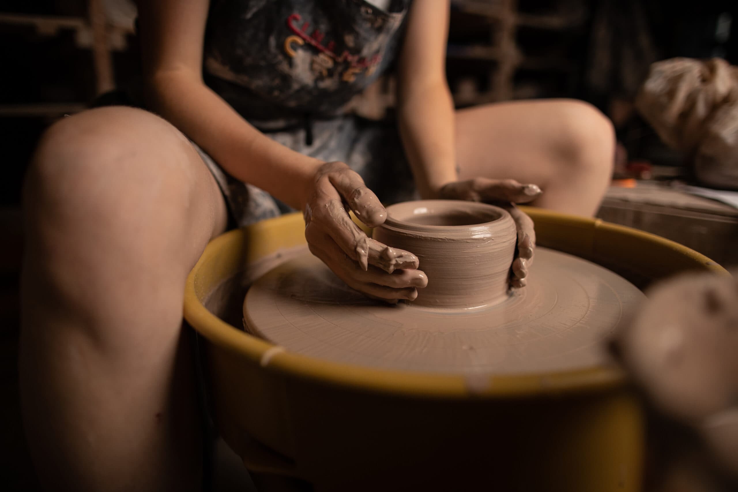 Berea College student making a clay bowl on the pottery wheel