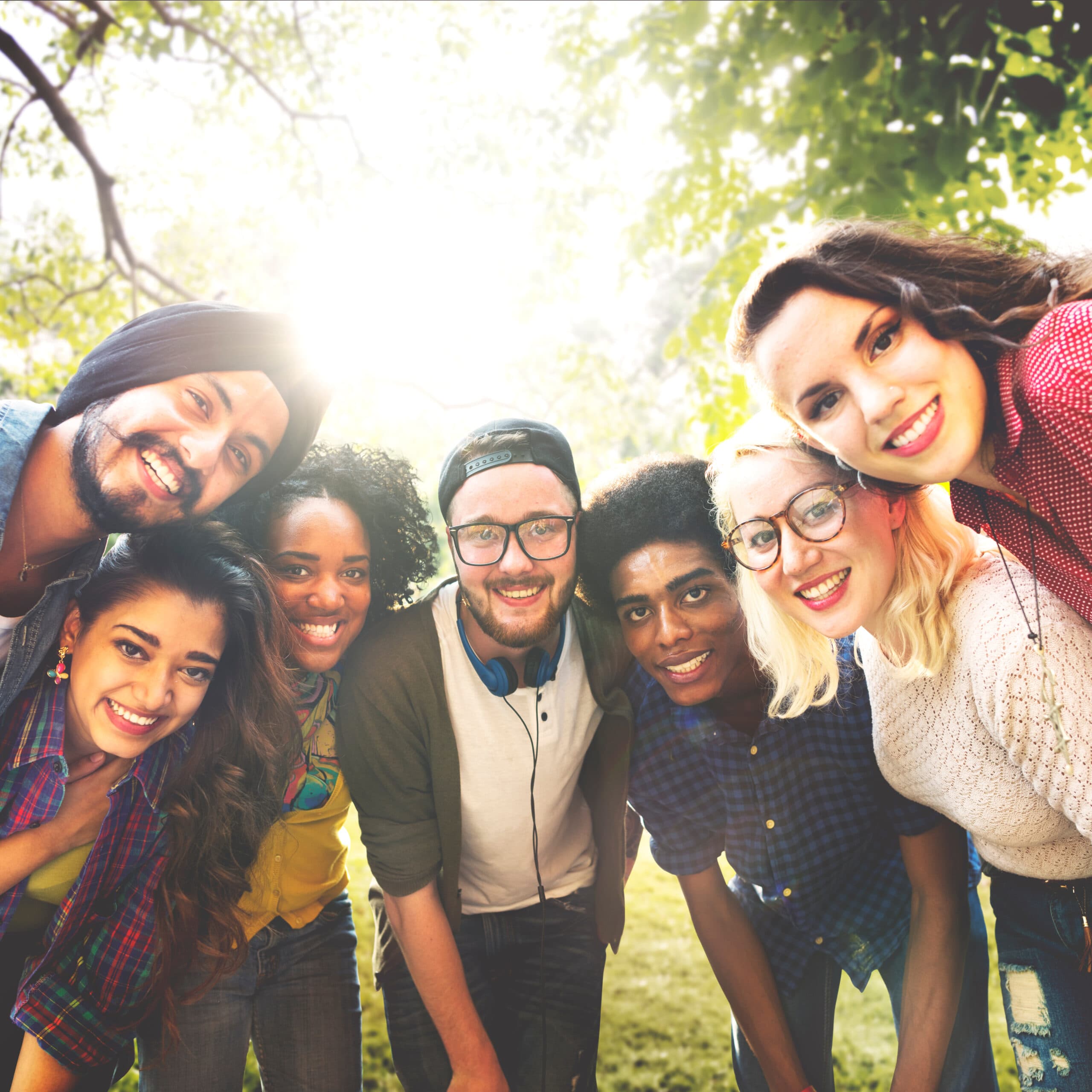 Group of diverse students smiling and huddled close together in semicircle