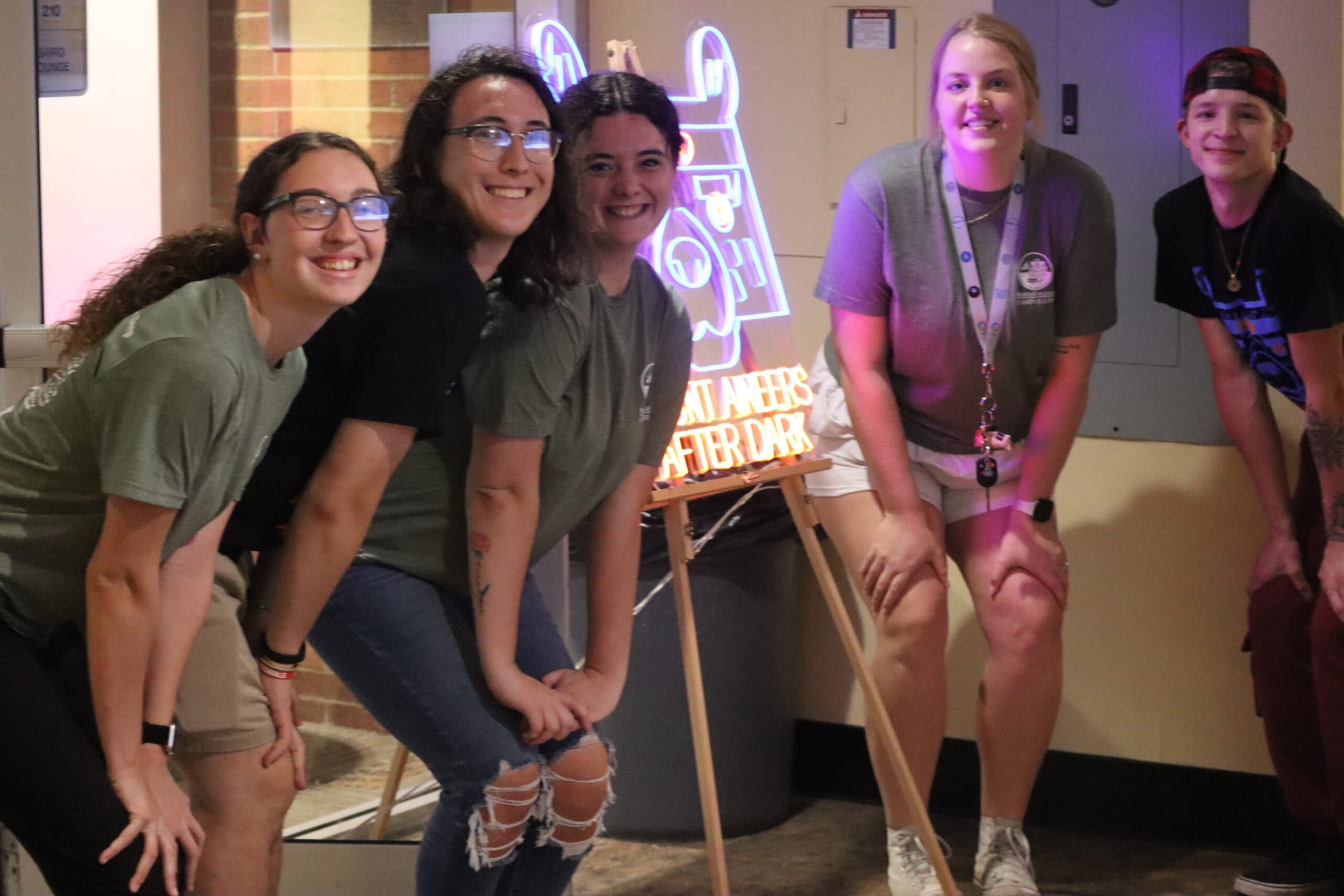 Students posing next to a neon sign