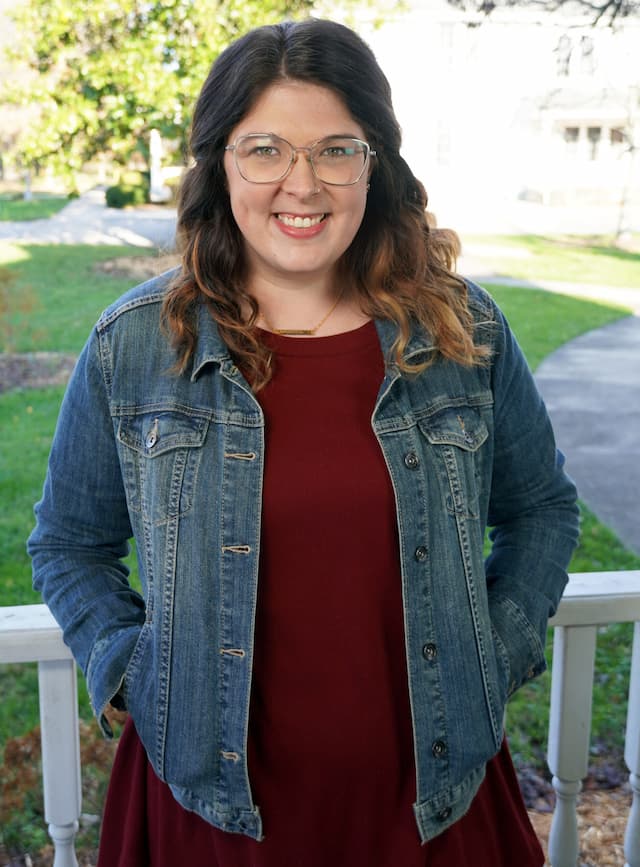 Berea College Admissions Counselor, Chelsea Bentley, leaning against a white fence, with green grass and a tree in the background.