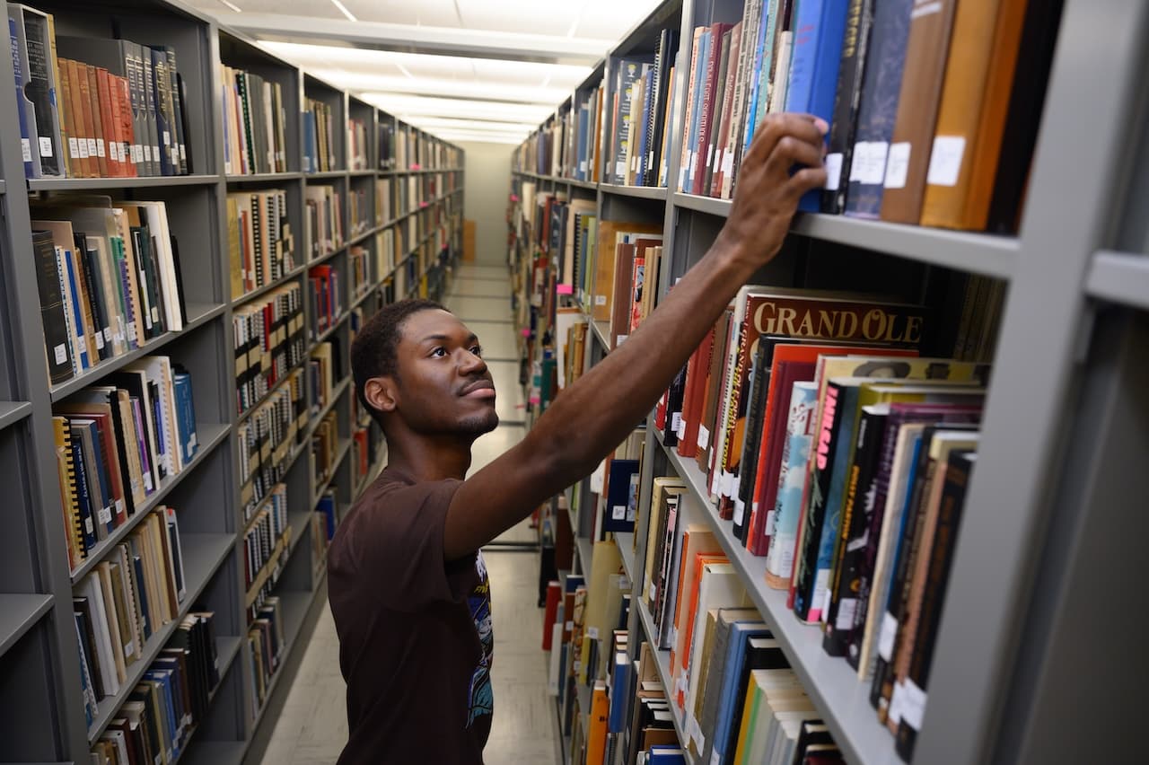 A Berea College student browsing through the shelves of Hutchins Library.