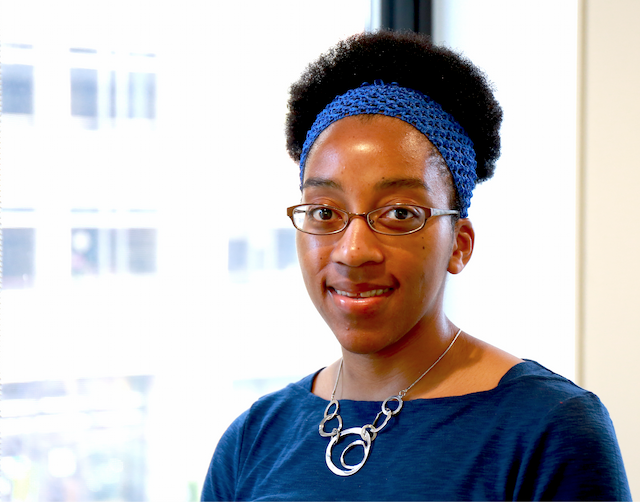 Jasmine Jones headshot with glass background and a blue shirt smiling.