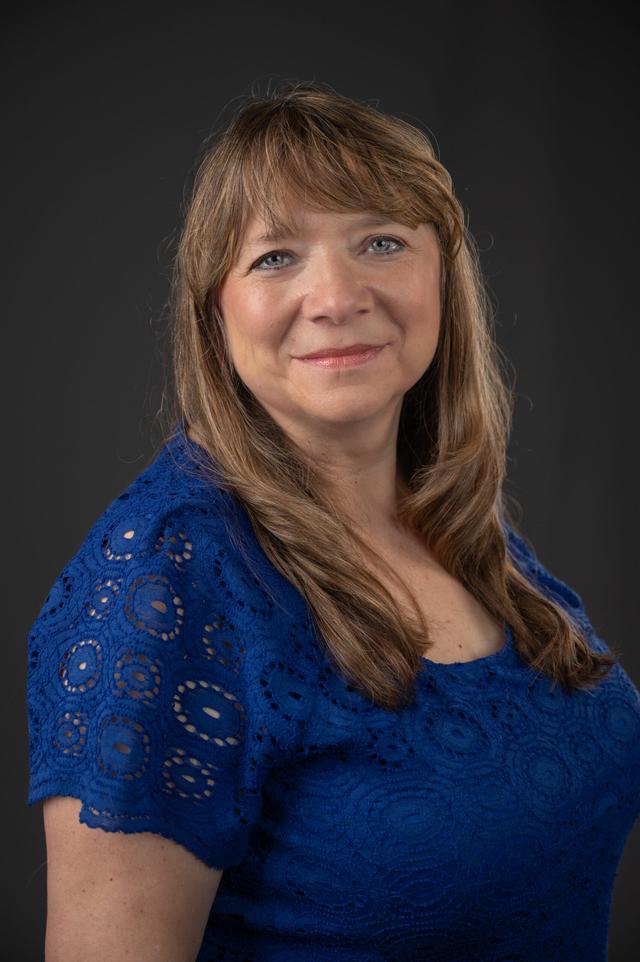 Gena Edwards Sonam Tsering sitting and wearing a blue dress with grey background